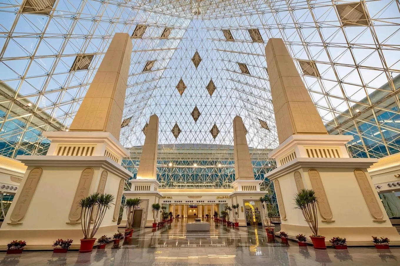 The main hall inside Bashtil Station, Cairo, with tall stone pillars carved with hieroglyphs under a glass pyramid roof