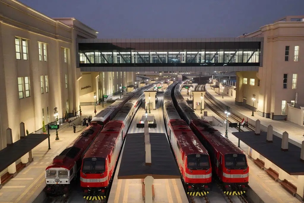 Sleeper trains waiting at the platforms of Bashtil Station, Cairo, at dusk, seen from the footbridge above