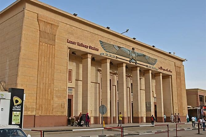 The front of Luxor Railway Station, a sandstone building with tall columns and a carved winged sun disc above the entrance